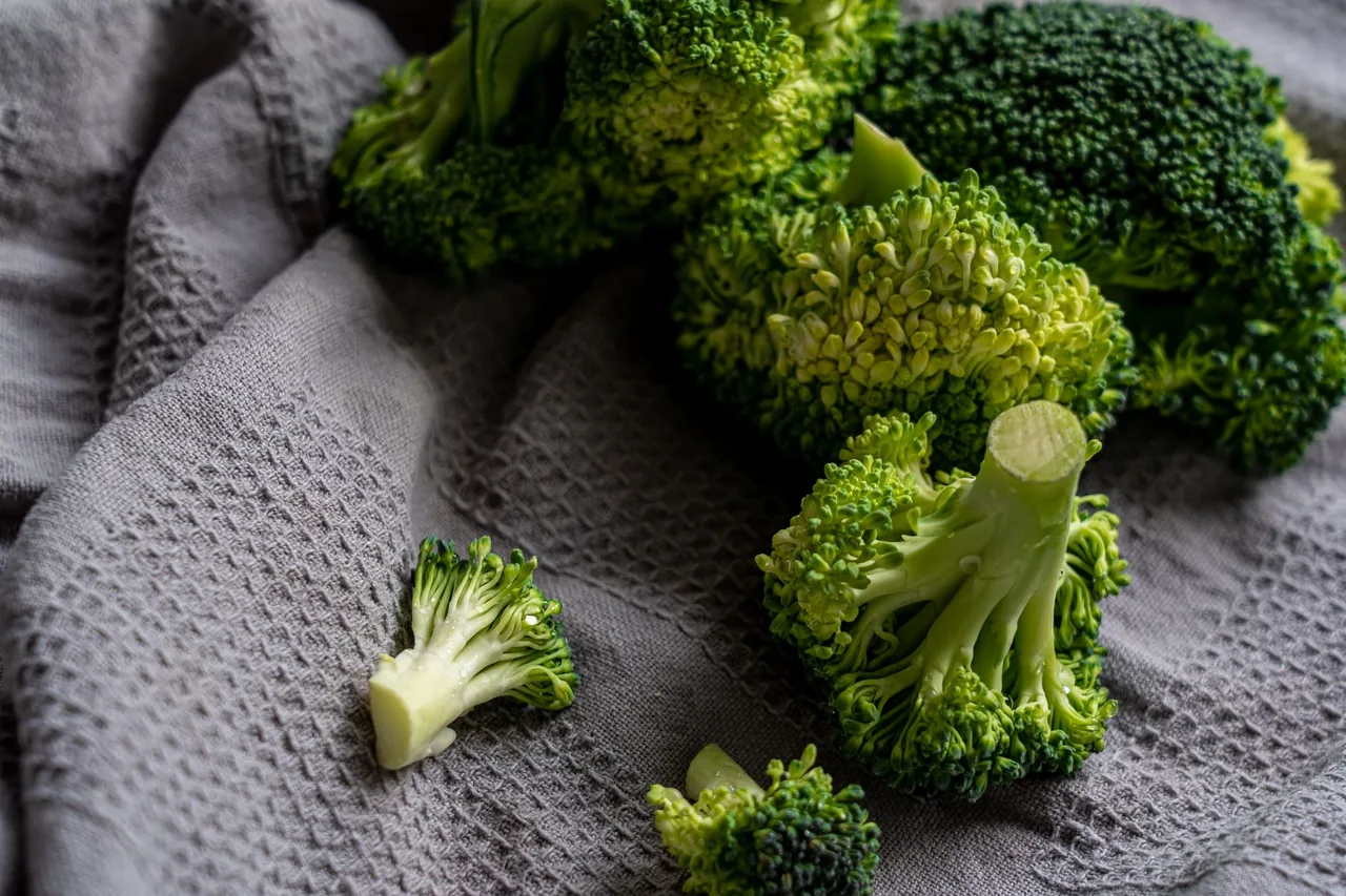 Broccoli florets and small cut pieces on a grey cloth.