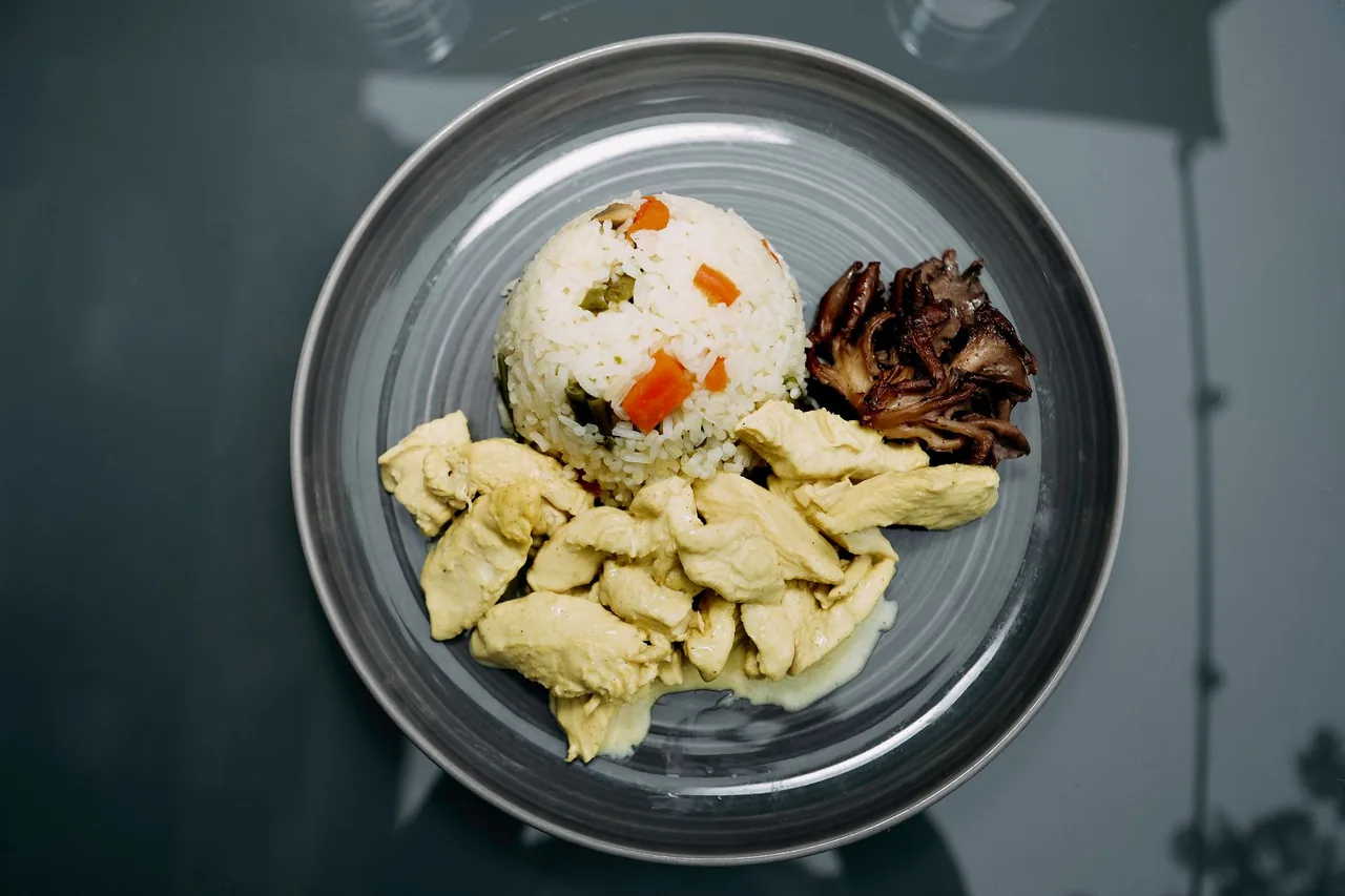 Trozos de pollo cocido sin condimentar junto a un montoncito de arroz en un plato gris.