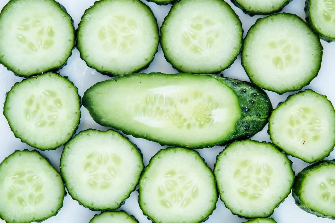 Round cucumber slices laid out around a cucumber cut in half lengthwise.