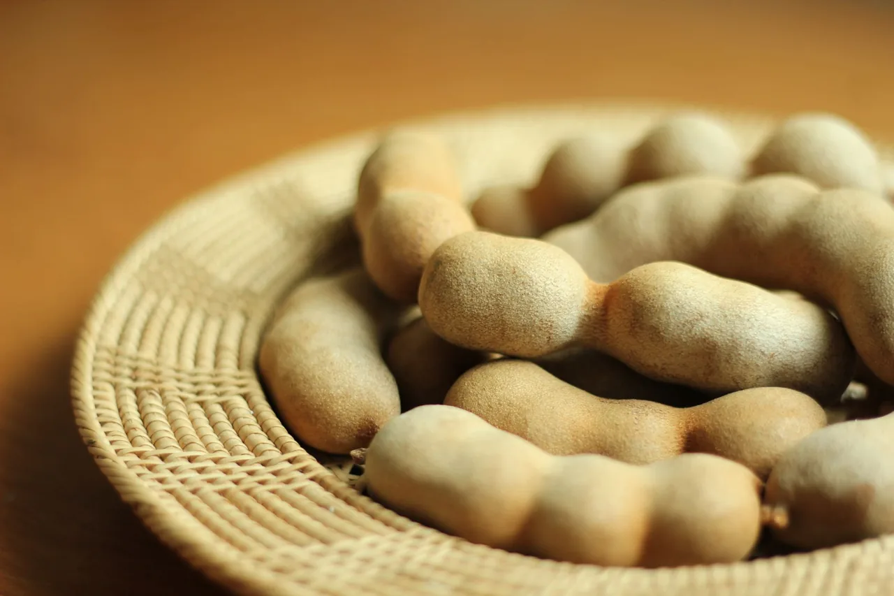 Brown tamarind pods in a woven basket.