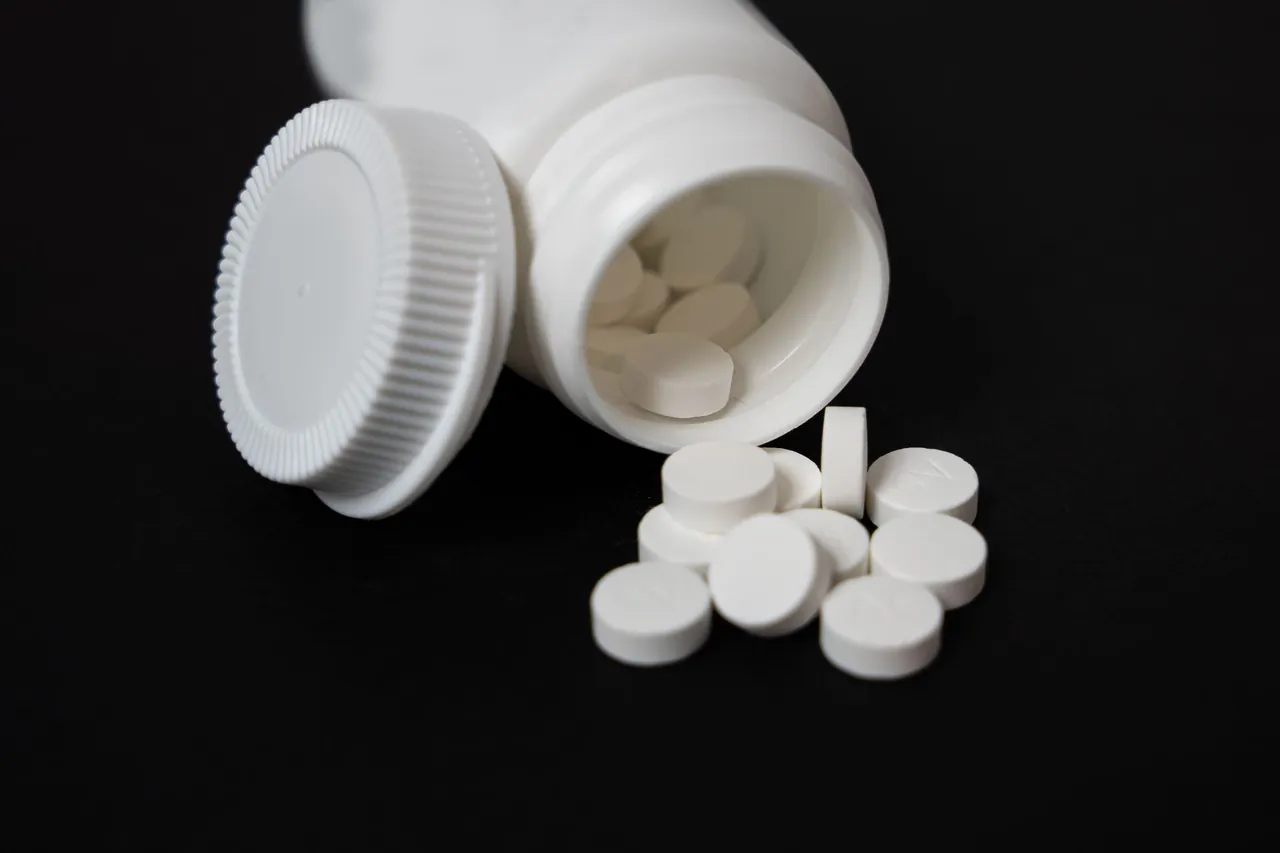 White tablets spilling from a white plastic bottle.