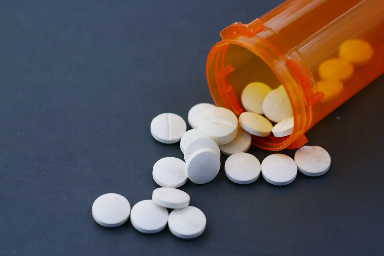 White tablets spilling out of an orange pill bottle.