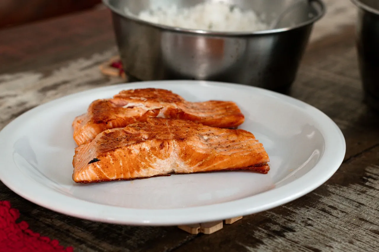 Two cooked salmon fillets on a white plate.