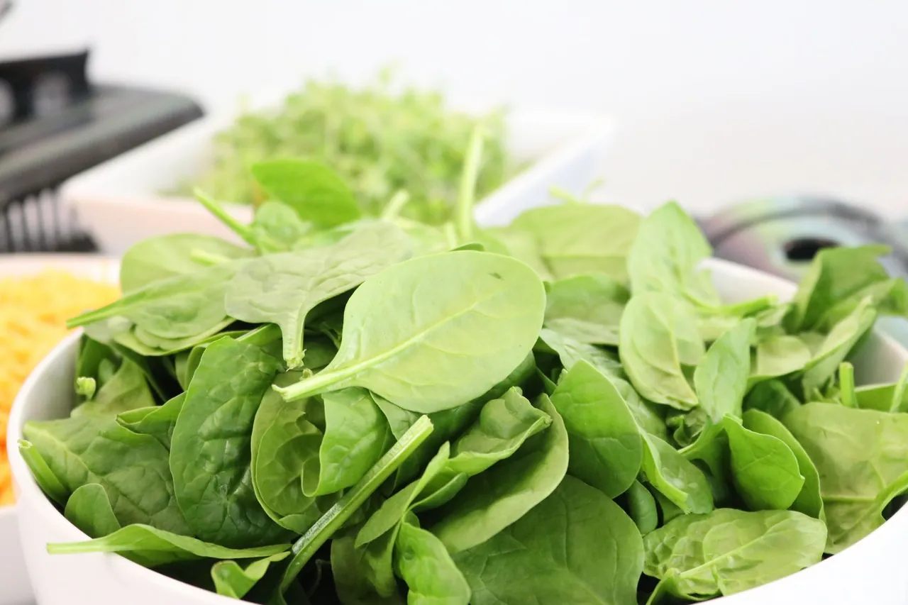 A white bowl filled with fresh spinach leaves.